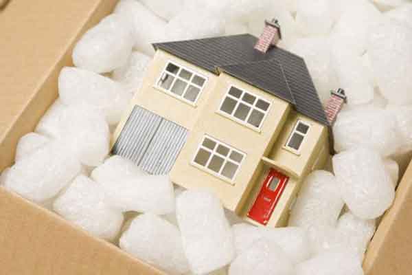 Picture of a toy house packed in a cardboard box with packing peanuts.
